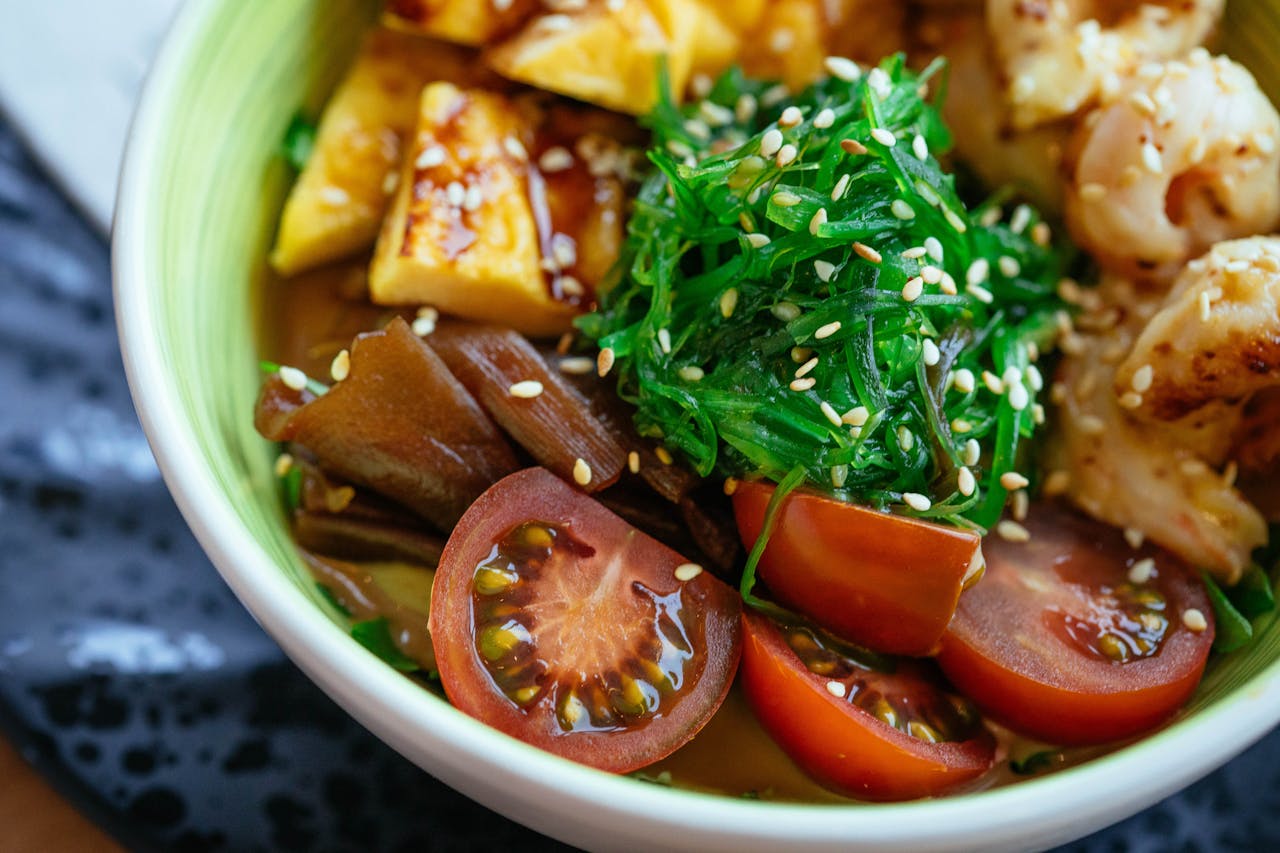 About A colorful vegan poke bowl with fresh vegetables, tofu, and sesame seeds.