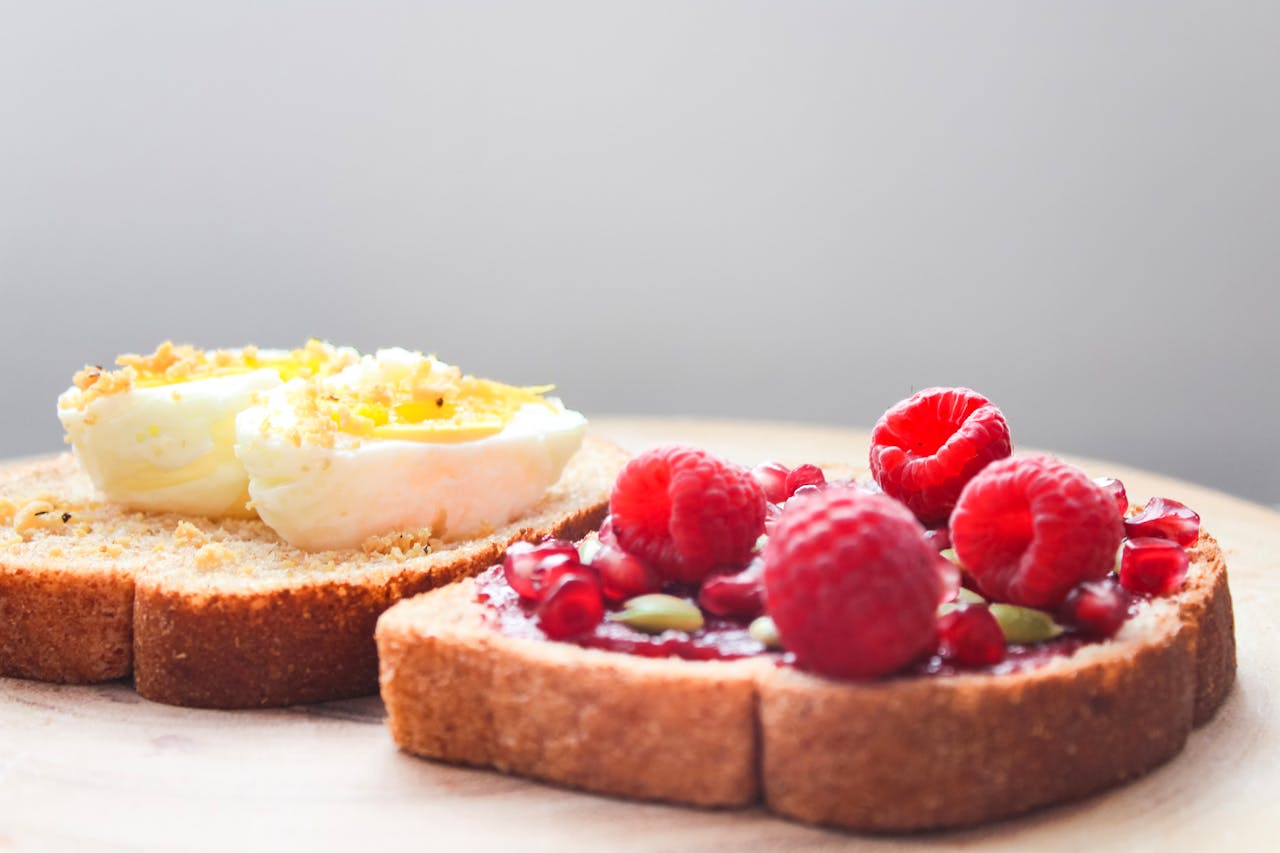 Close-up of a nutritious breakfast toast featuring eggs and berry jam topped with fresh raspberries.