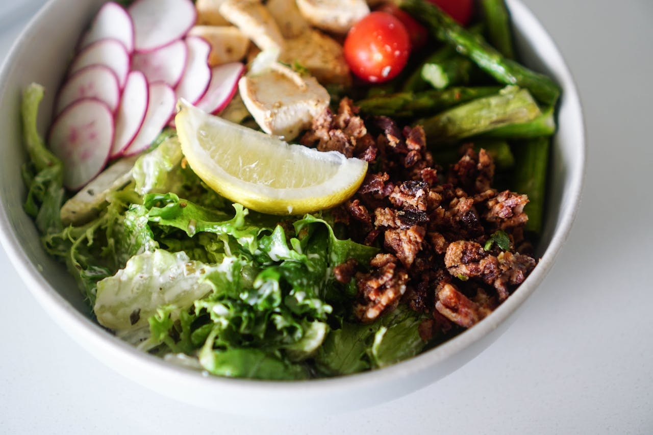 Delicious and vibrant salad bowl featuring fresh greens, chicken, and lemon slice.